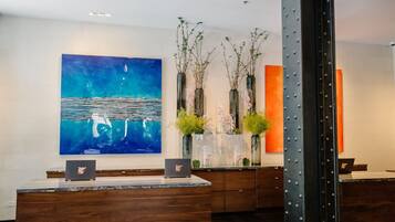 A modern reception area with a wooden reception desk, a large abstract painting, and a tall metal column.