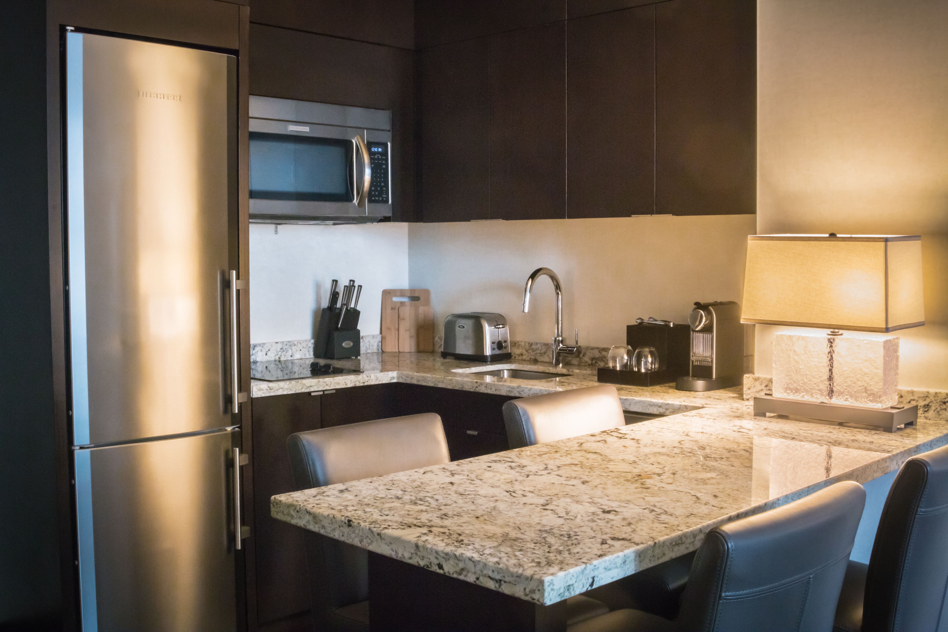 Una cucina moderna con frigorifero, forno a microonde, tostapane, lavello e un piano di lavoro in marmo.