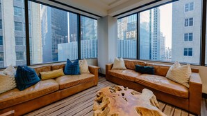 A modern living room with two leather sofas, a wooden coffee table, and large windows offering a city view. - JW Marriott Houston Downtown (Houston)