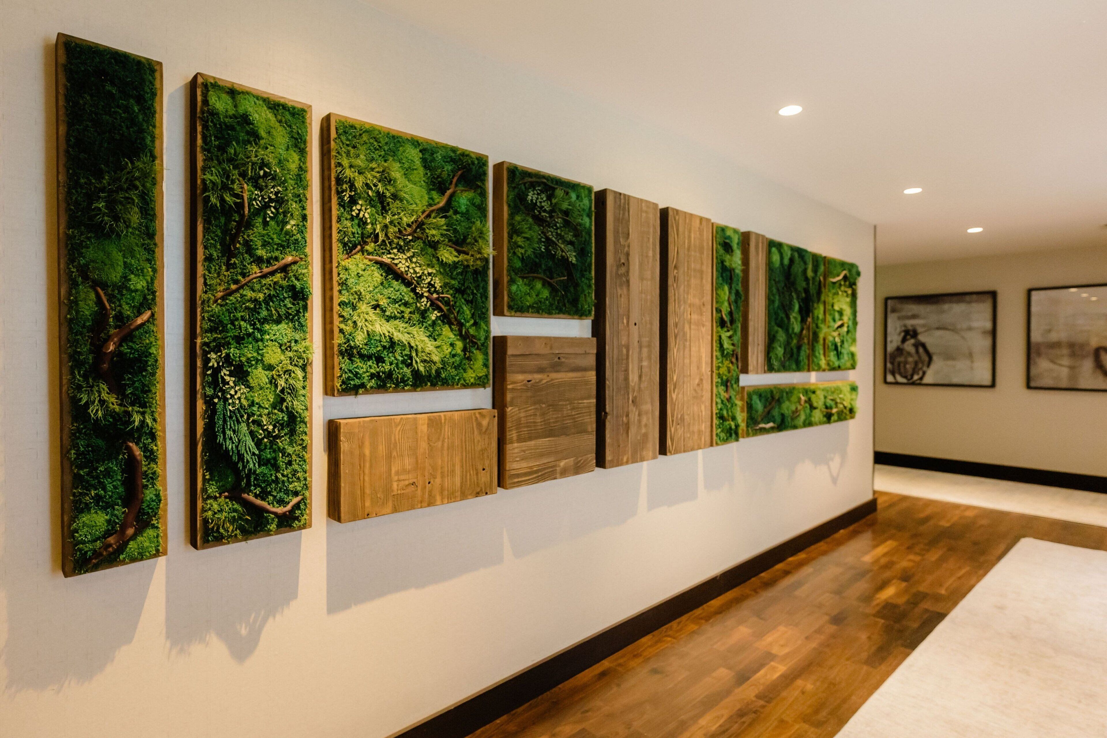 Een gang met verticale panelen waarop een boslandschap, houten lambrisering en ingelijste kunst te zien is.