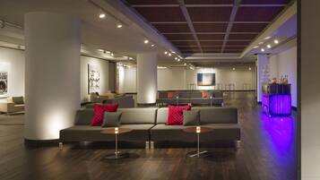 A modern lobby with a sofa, a bar area, and a large wall with the text "PICASSO".