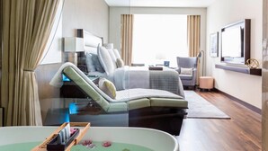 A modern hotel room with a large bed, a seating area with a chaise lounge, a flat-screen TV, and a large window with curtains. - JW Marriott Houston Downtown (Houston)