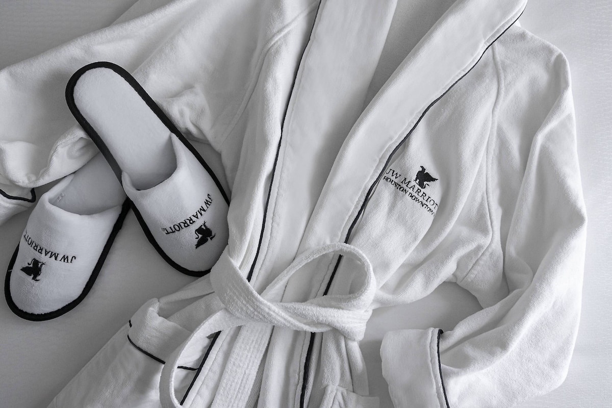 Un peignoir blanc et des chaussons ornés d’un motif brodé.
