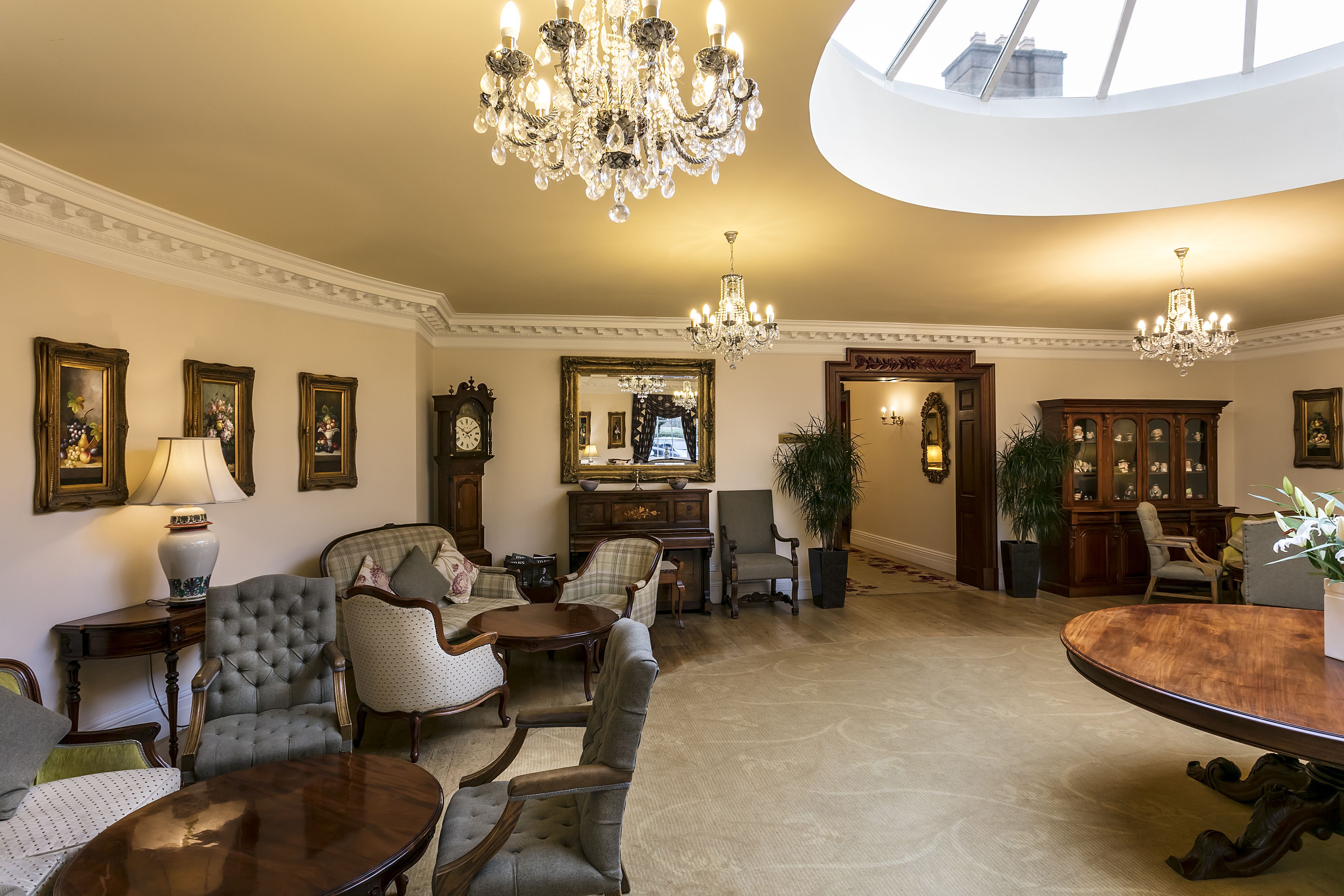 Amplia habitación con una gran mesa de comedor, varias sillas, un candelabro y un espejo grande.