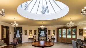 A grand room with a large round table, elegant chairs, chandeliers, and a skylight. - Doxford Hall Hotel & Spa (Chathill)