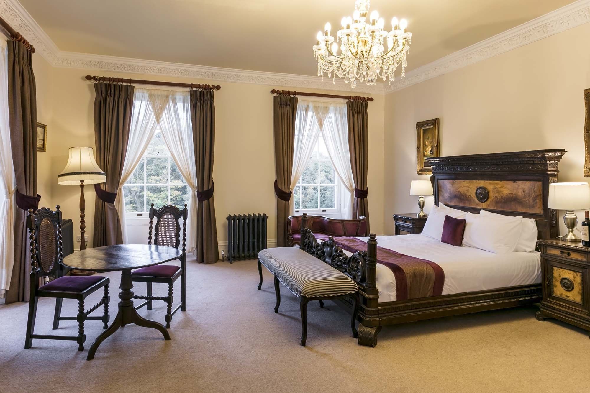 Una camera d'albergo classica con un letto grande, un tavolo da pranzo e un lampadario.