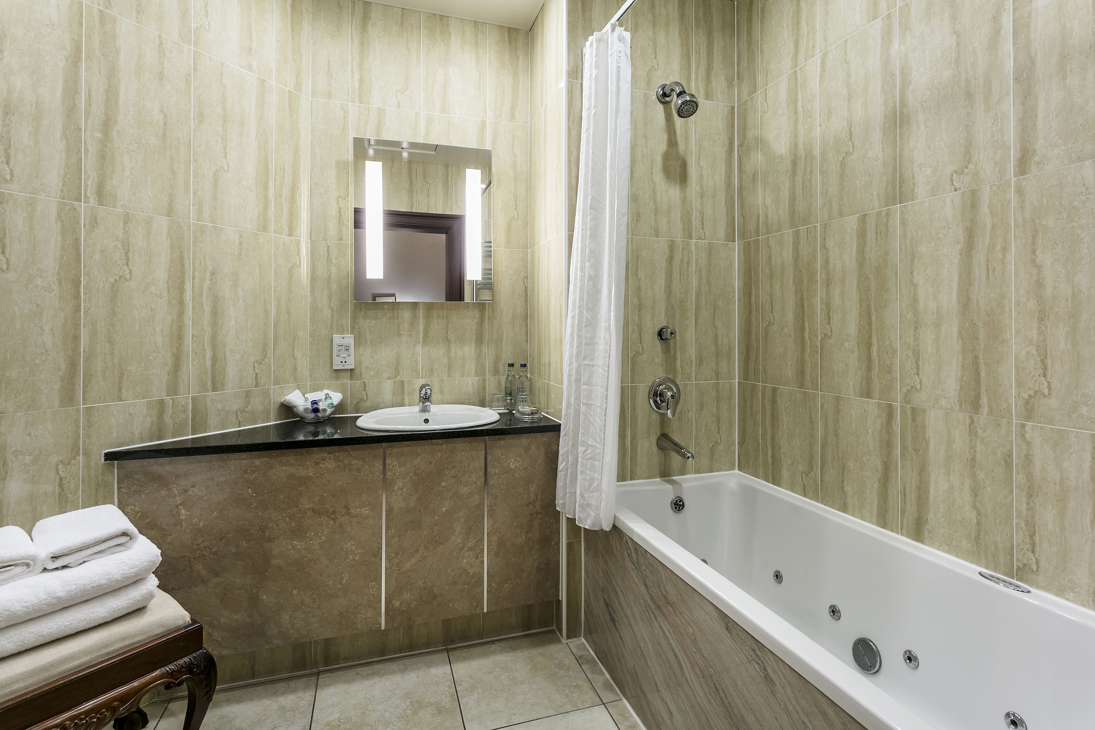 Een badkamer met een bad, een wastafel en een spiegel.