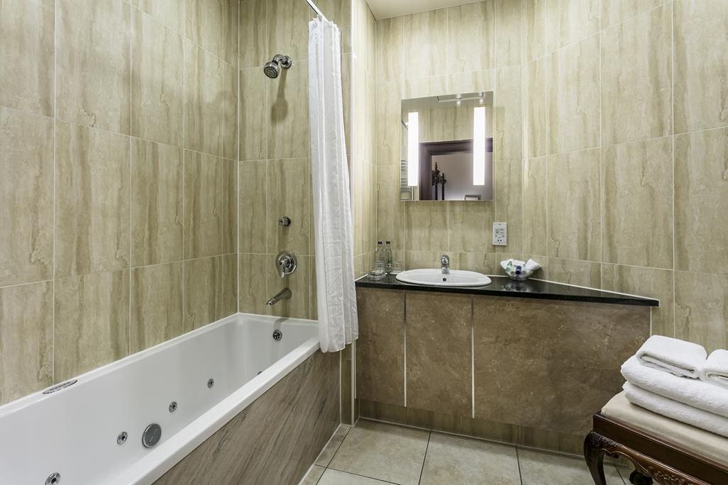 A bathroom with a bathtub, a sink, and a mirror.