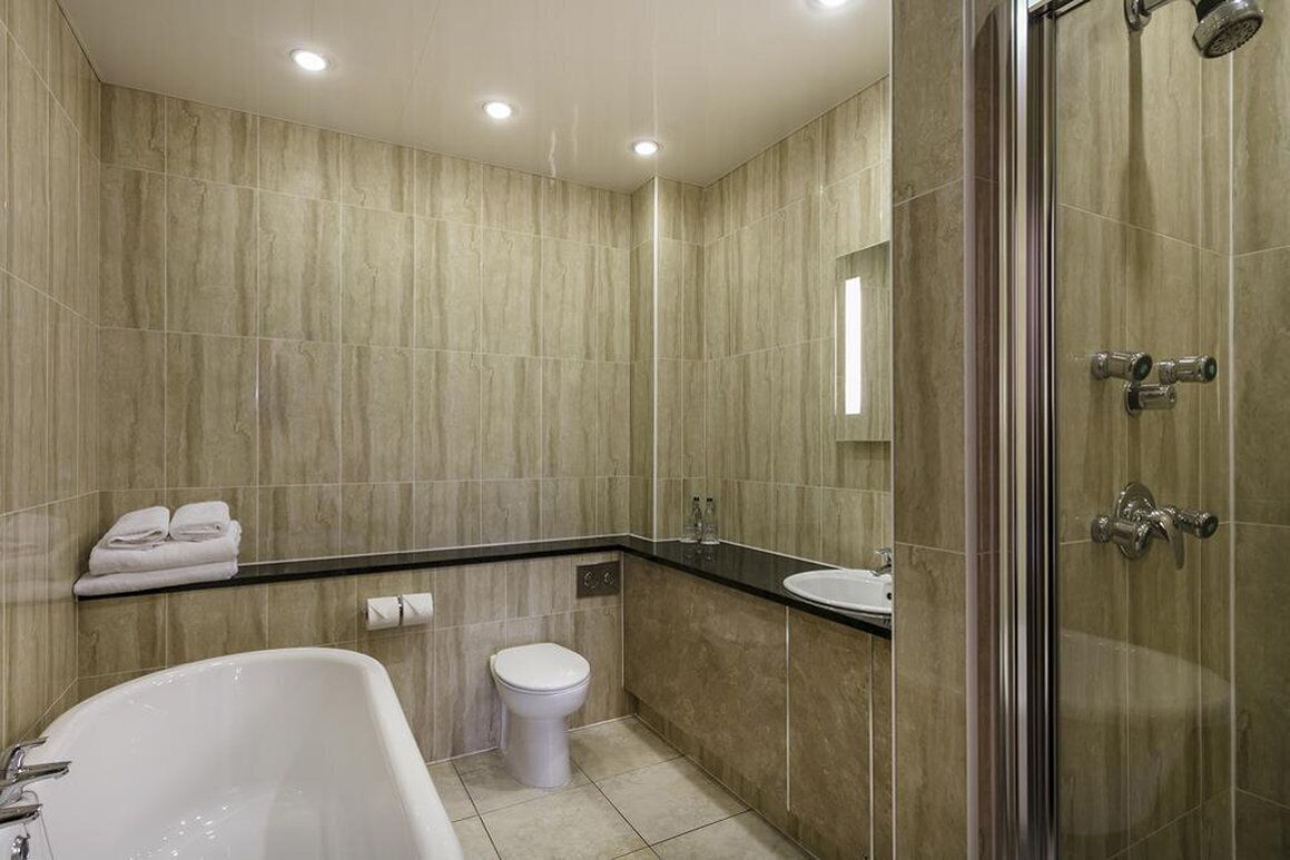 Un baño moderno con bañera, inodoro y zona de ducha.