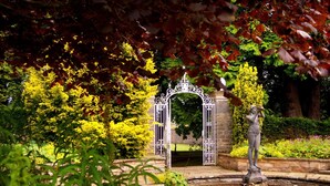 A garden with a fountain, a statue, and an ornate gate. - Doxford Hall Hotel & Spa (Chathill)