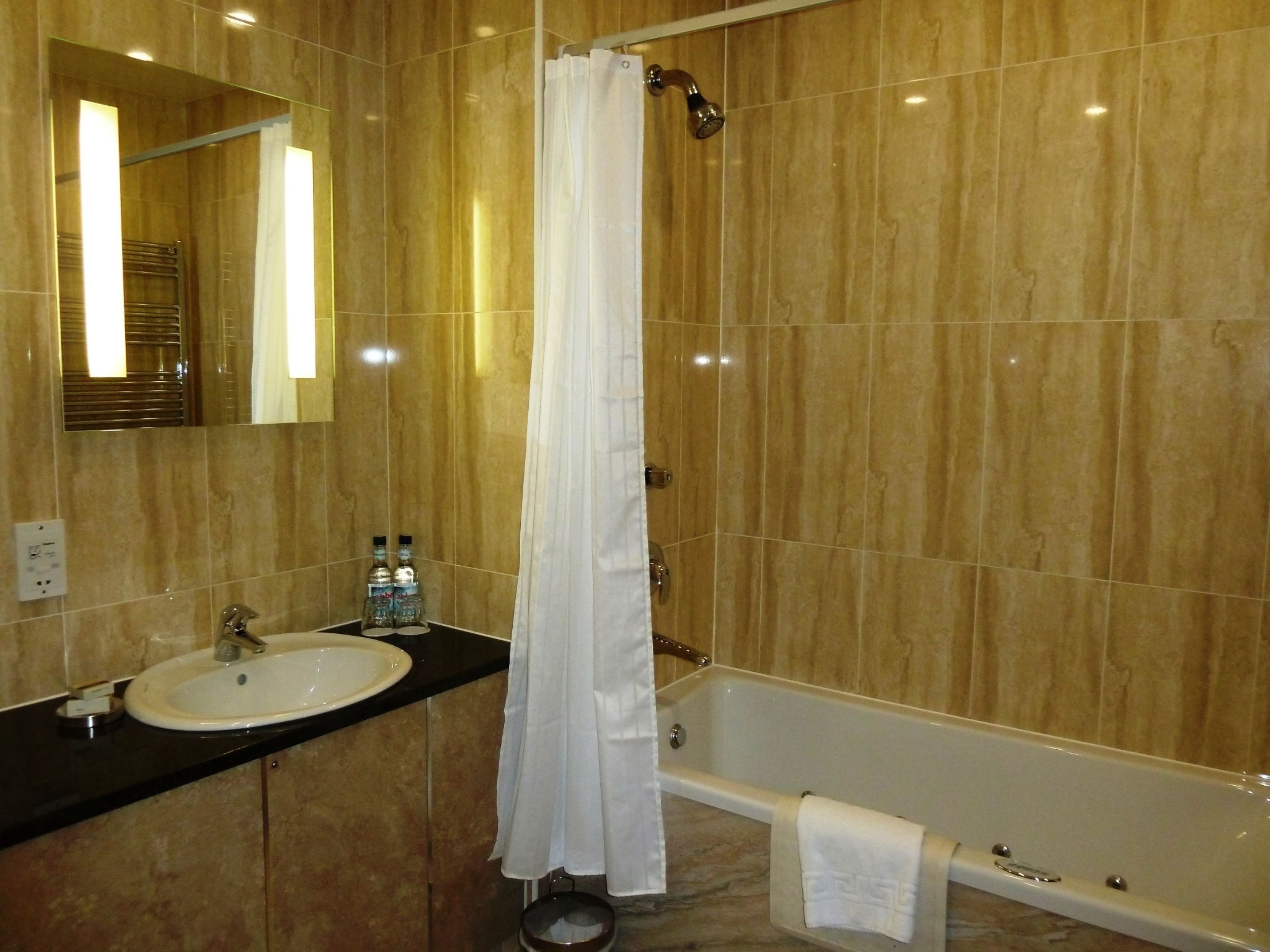 A bathroom with a bathtub, a sink, and a mirror.
