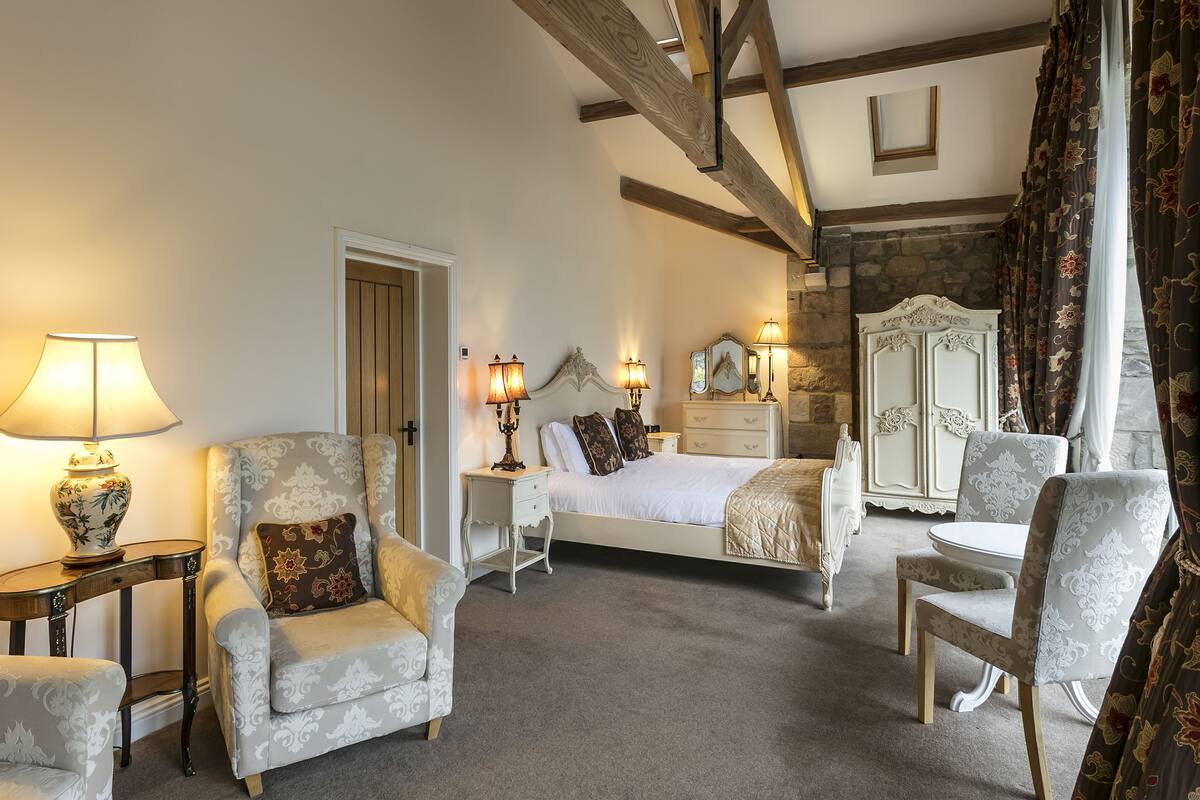 A bedroom with a bed, two nightstands, a dresser, a chair, and a table.