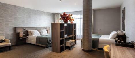 A modern hotel room with a bed, a sofa, a wooden bookshelf, and a coffee table.