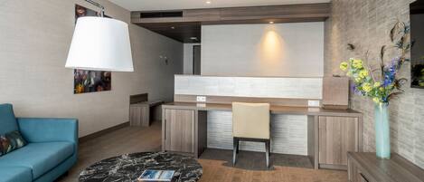 Una sala moderna con un sofá azul, una mesa de centro de mármol y una zona de cocina con barra.