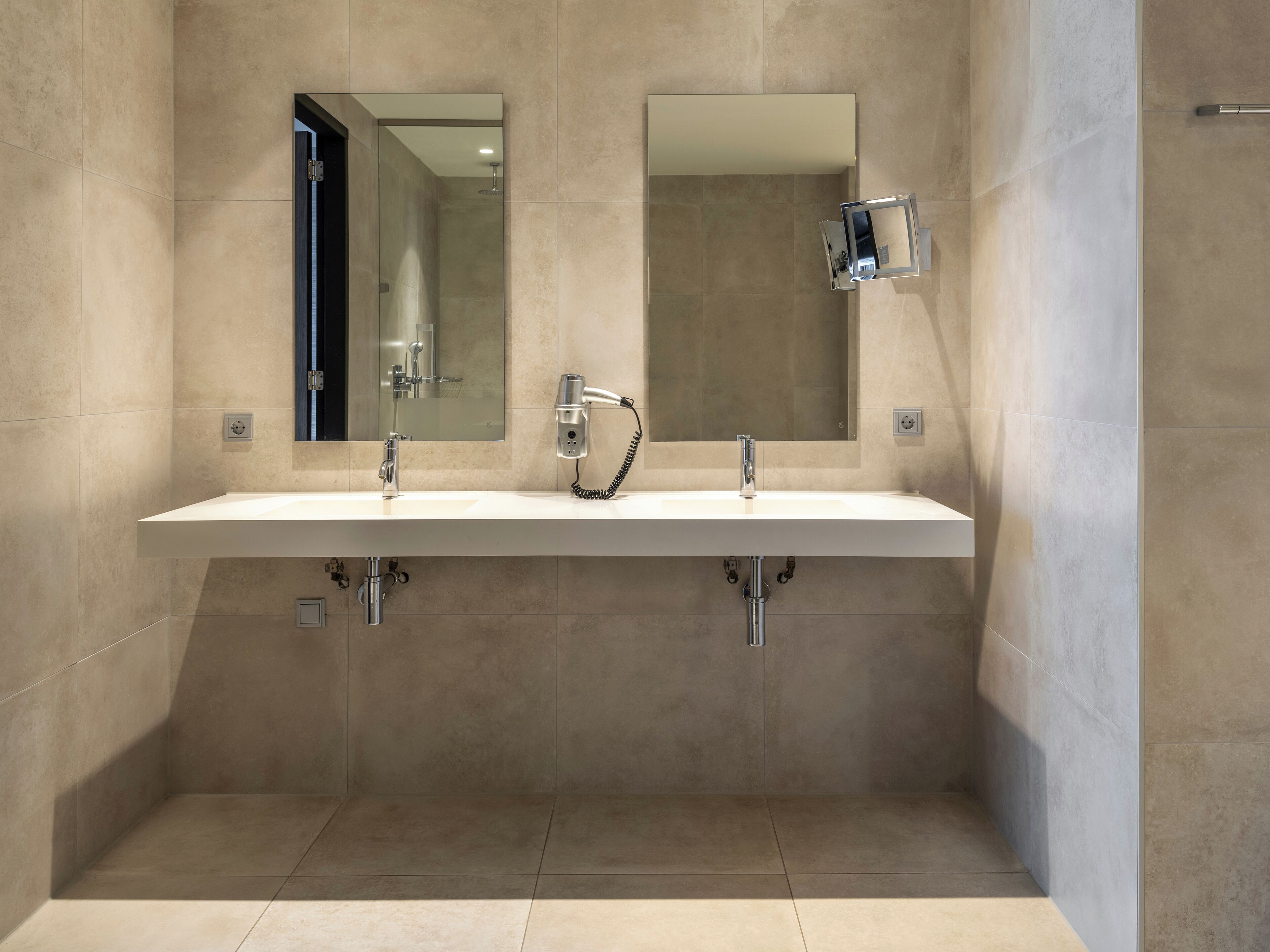 Un baño moderno con lavamanos doble, espejo y ducha.