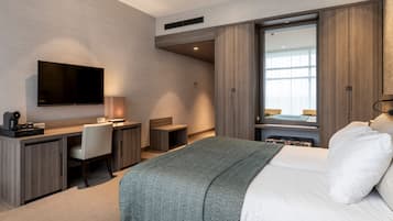 Quarto de hotel moderno com cama, escrivaninha, cadeira, televisão e guarda-roupa.