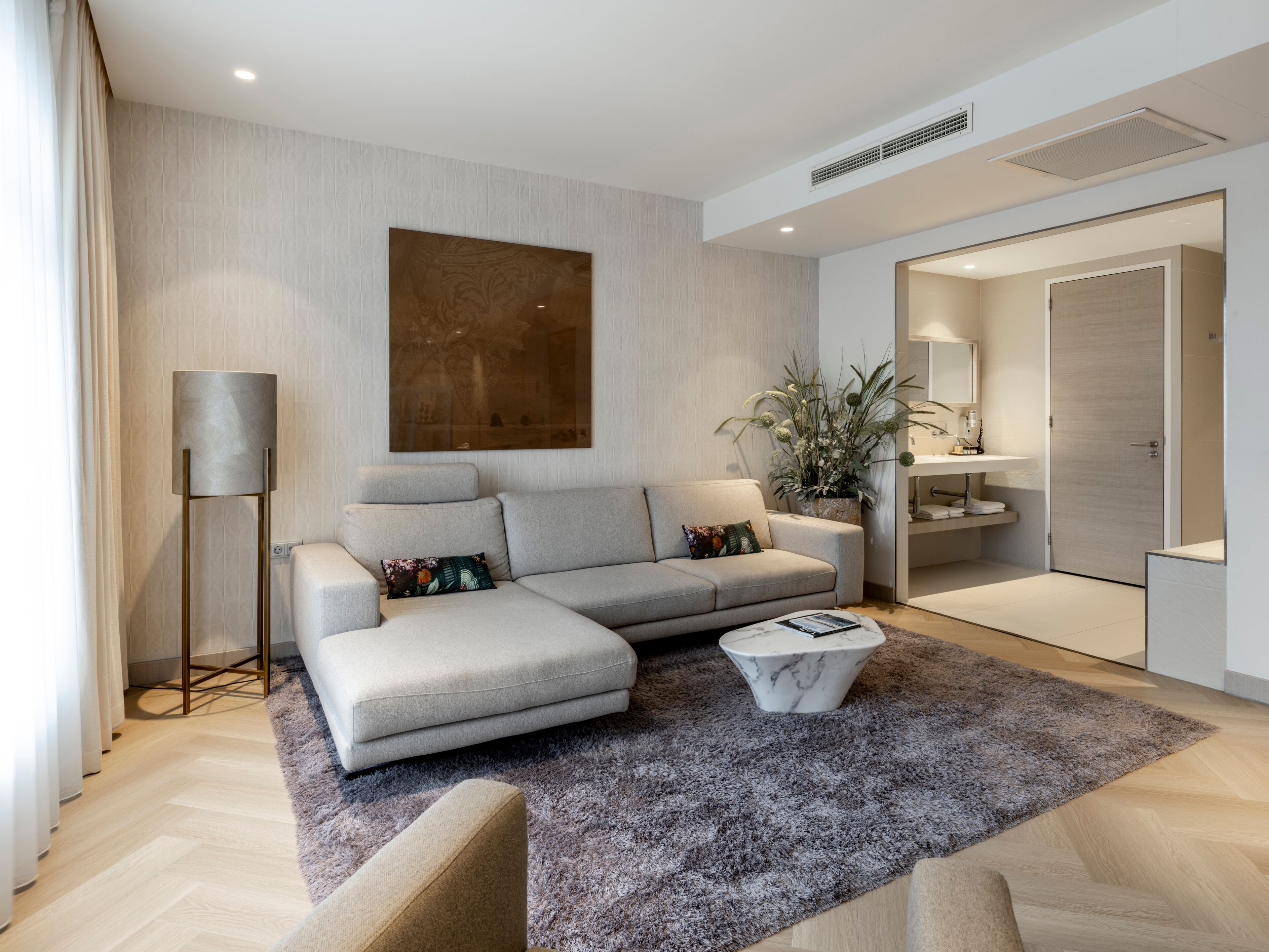 A modern living room with a sectional sofa, a coffee table, and a large abstract painting on the wall.