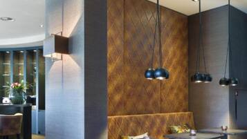 Un interior moderno con una zona de estar, iluminación colgante y un papel tapiz estampado.