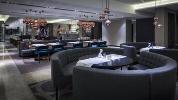 A modern restaurant with round tables and grey upholstered seating.