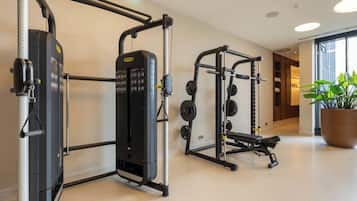 A gym with weightlifting equipment, a bench, and a potted plant.