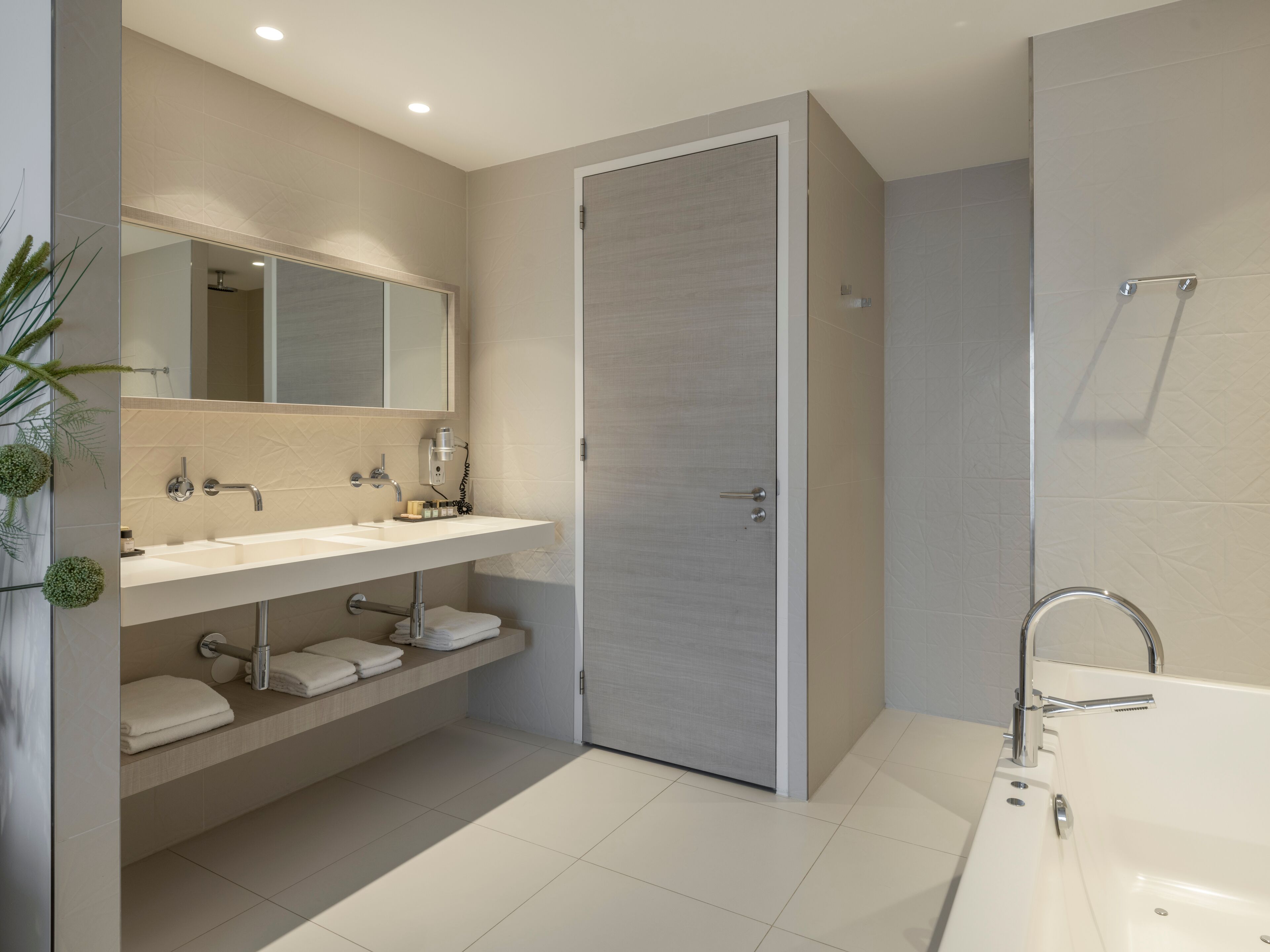 A modern bathroom with a large bathtub, a double sink vanity, and a walk-in shower.