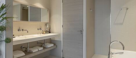 Un baño moderno con una bañera grande, un tocador doble y una ducha a ras de suelo.