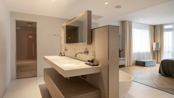 A modern bathroom with a large sink, mirror, and bathtub.