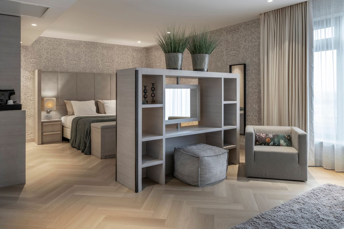 A modern bedroom with a bed, bedside table, lamp, and a grey sofa.