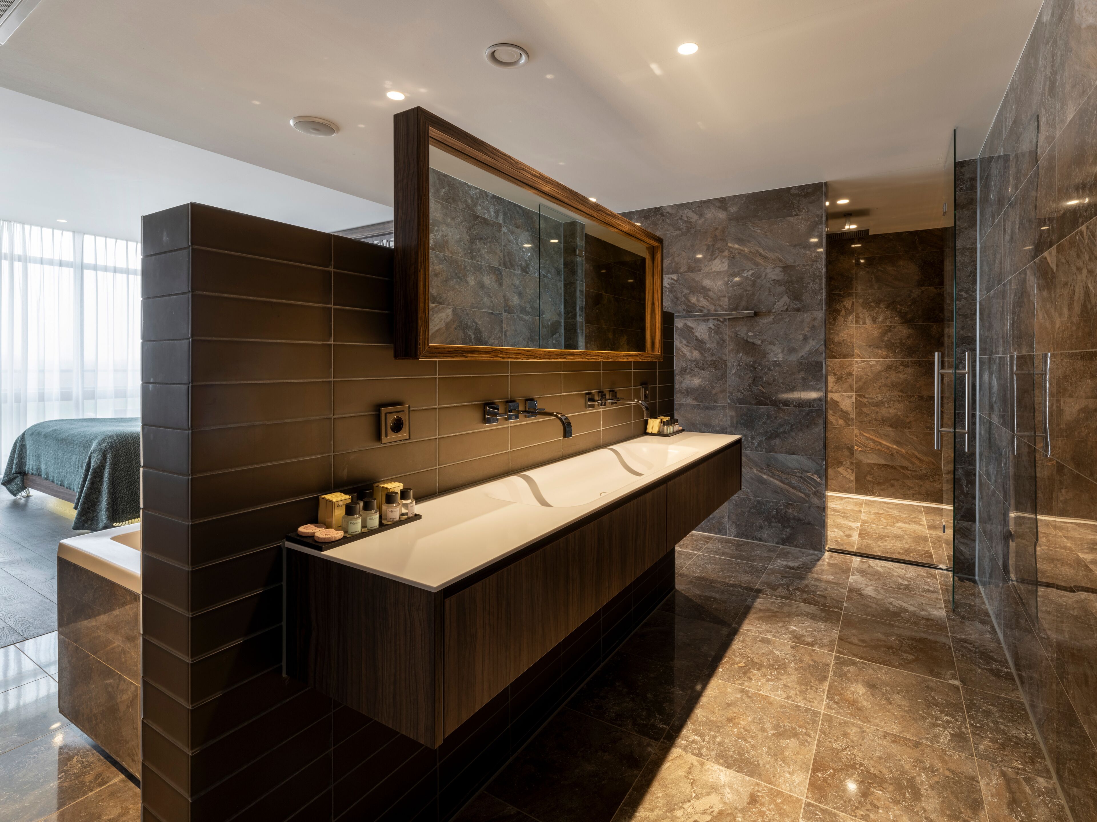 A modern bathroom with a large mirror, dark wood cabinetry, and a marble shower area.