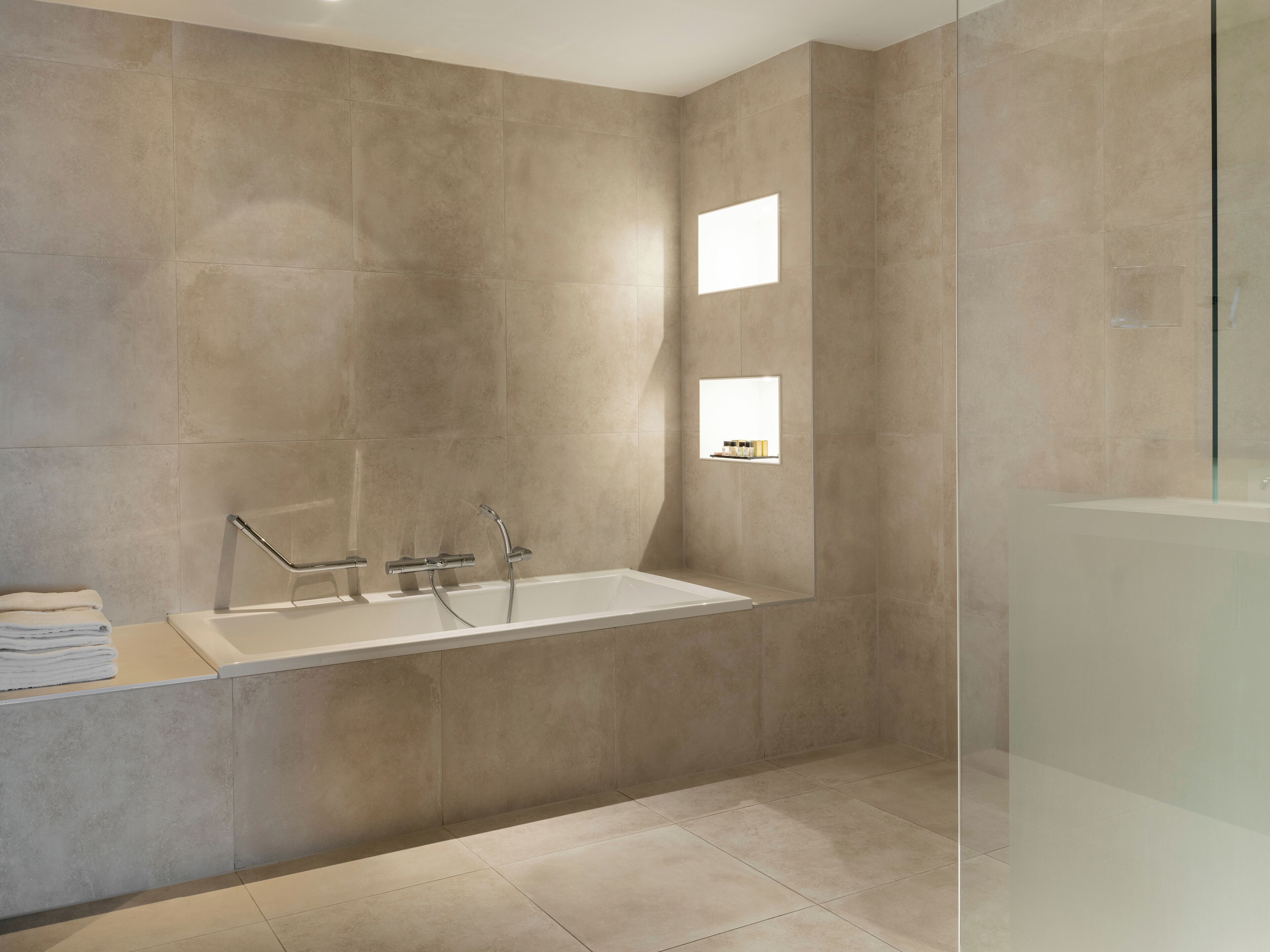Un baño moderno con una bañera independiente, cabina de ducha de vidrio y un estante pequeño con artículos de aseo.