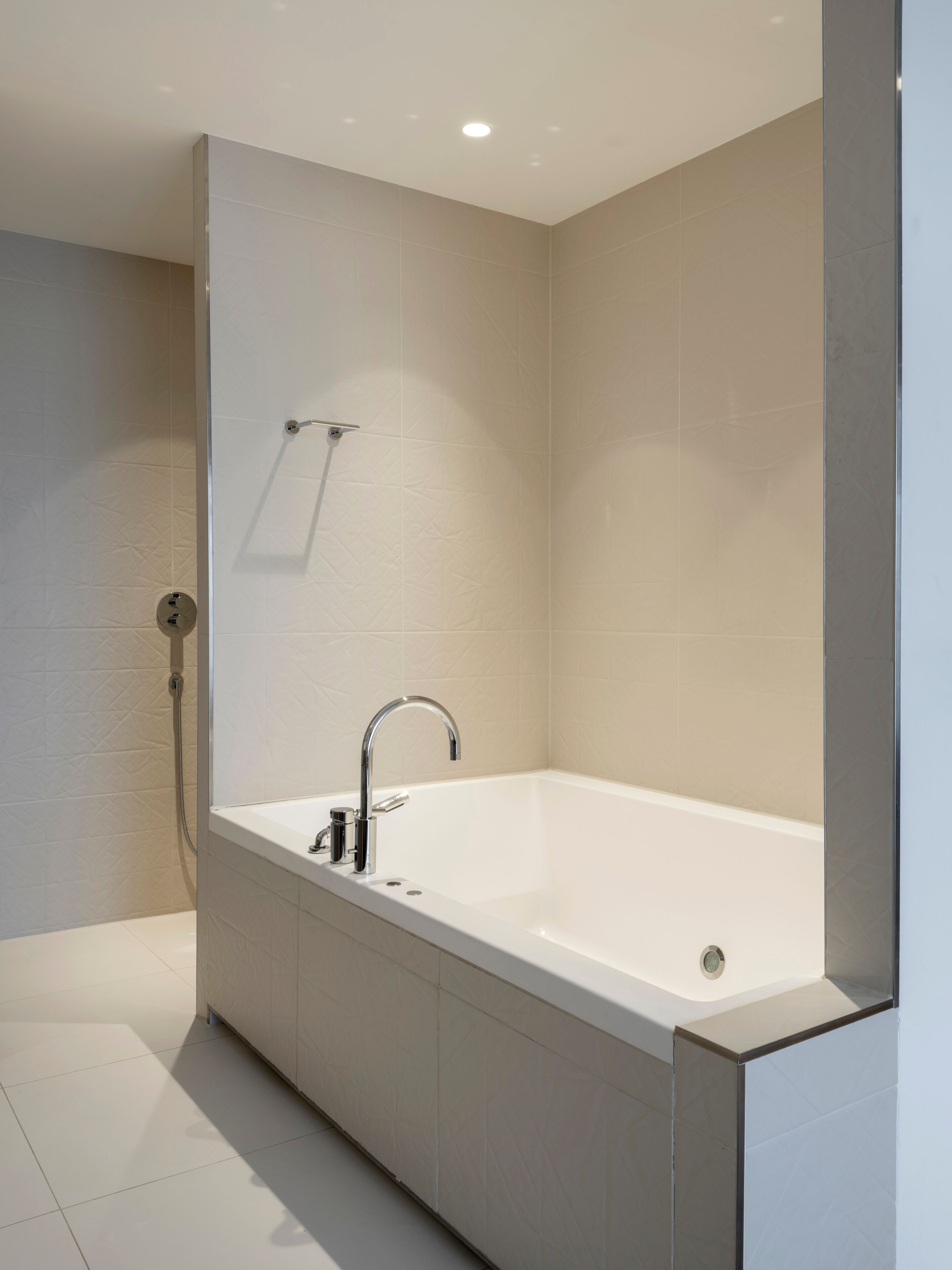 A modern bathroom with a freestanding bathtub, a handheld showerhead, and a wall-mounted towel rack.