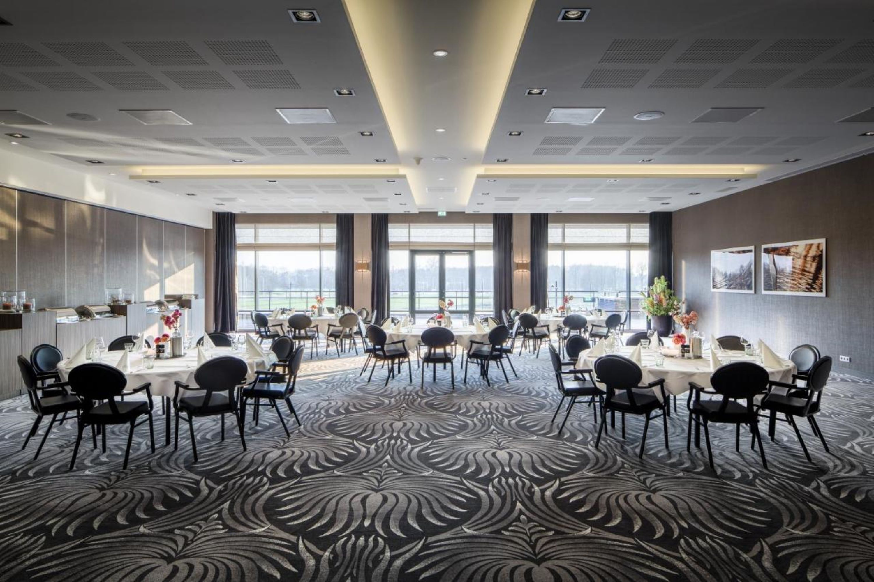 A conference room with a patterned carpet, large windows, and a modern ceiling design.