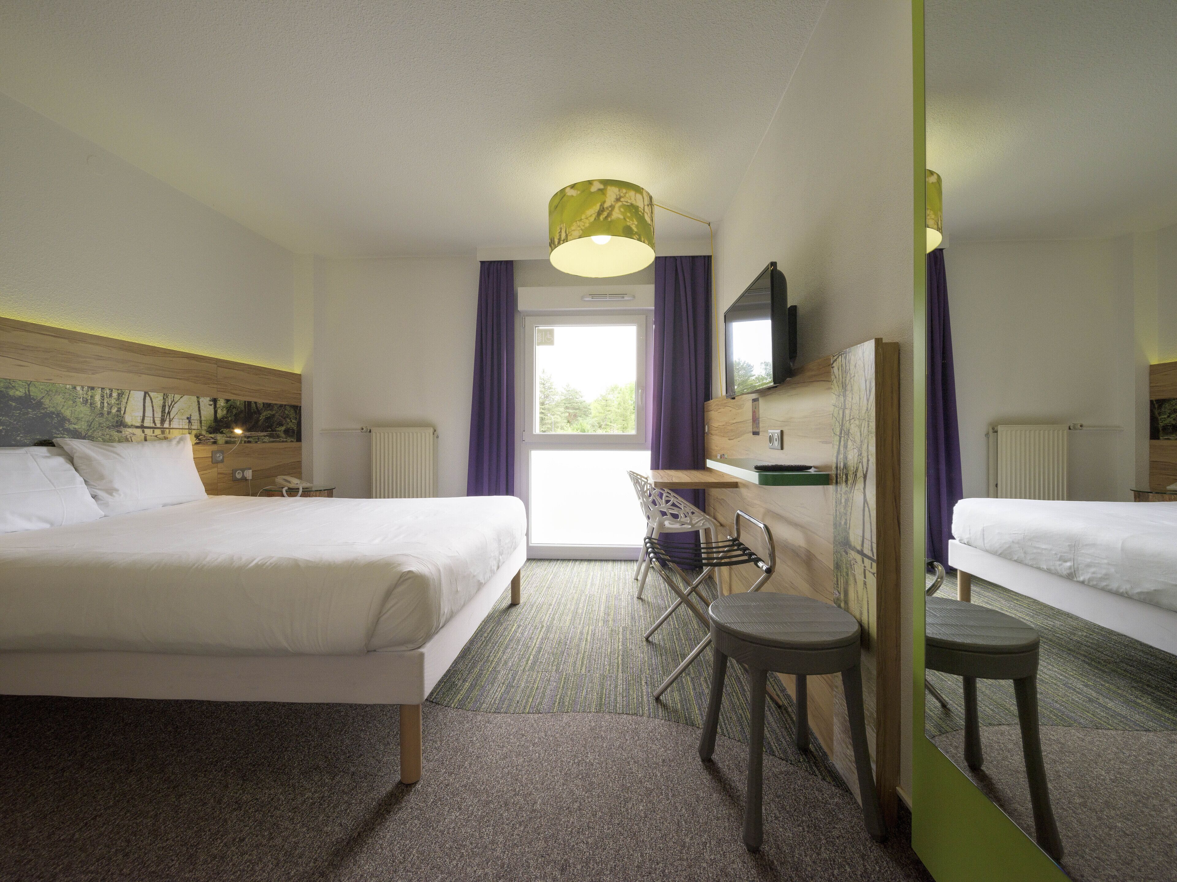 A hotel room with two beds, a desk, a chair, a TV, and a window with curtains.