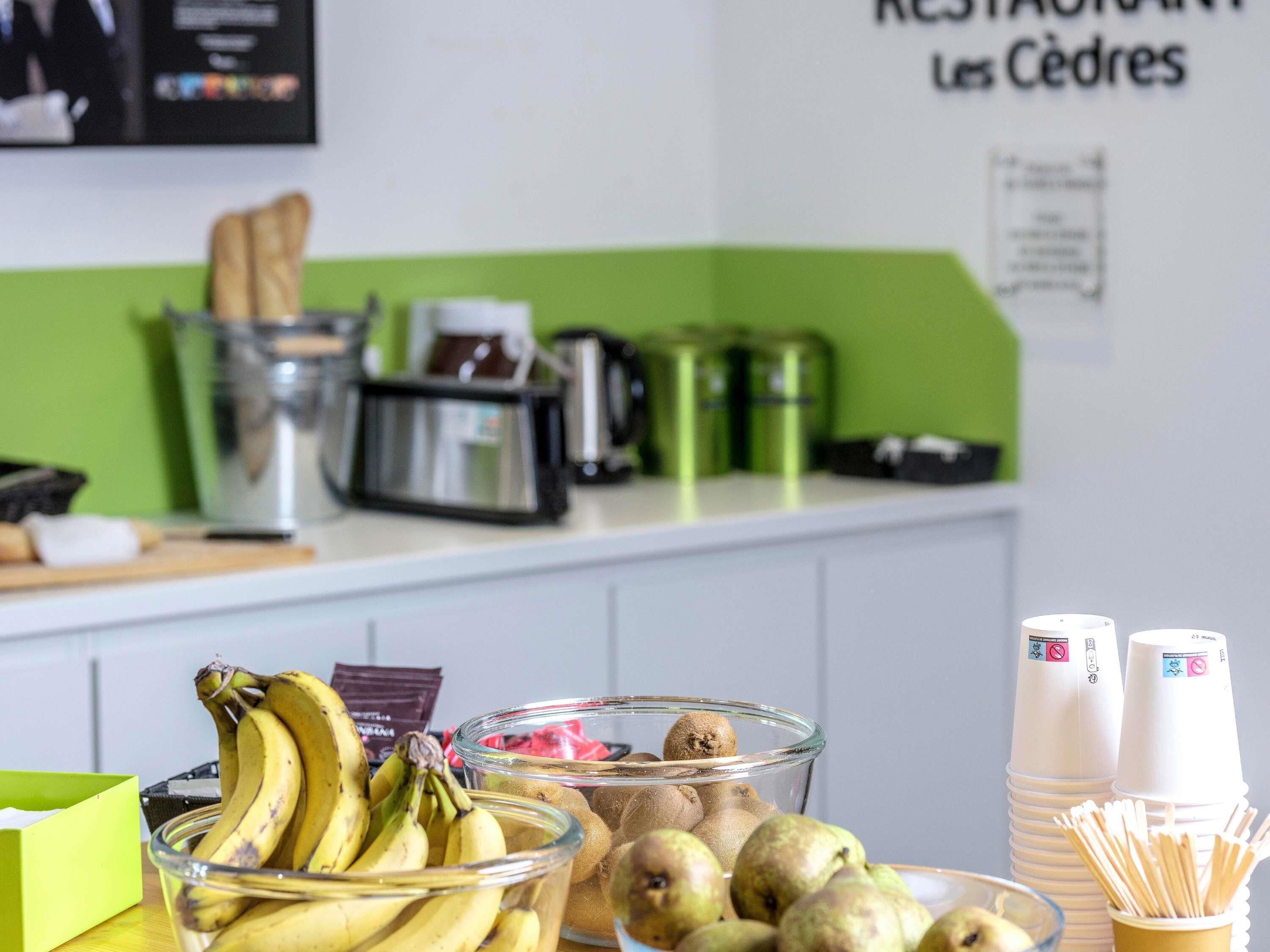 A kitchen counter with bananas, kiwis, and a coffee machine.
