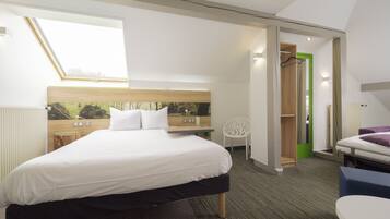 Habitación de hotel moderna con una cama grande, un escritorio pequeño, una silla y vistas al exterior a través de un tragaluz.