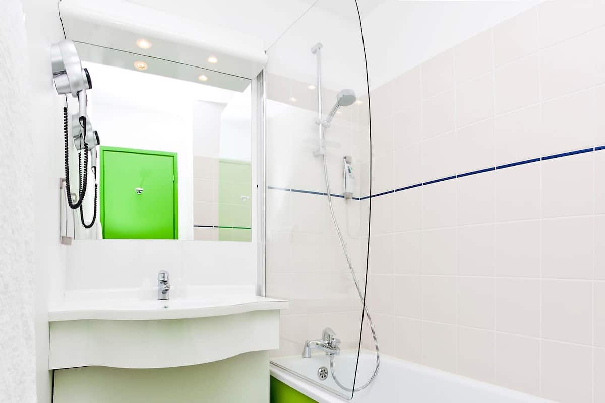 Ein modernes Badezimmer mit einem weißen Waschbecken, einer grünen Akzentwand und einer Duschkabine.