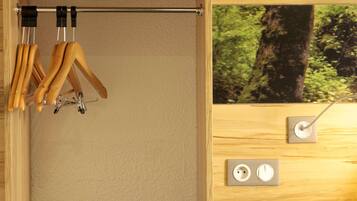 A wooden wardrobe with a hanging rod for clothes and a mirror with a view of a forest.