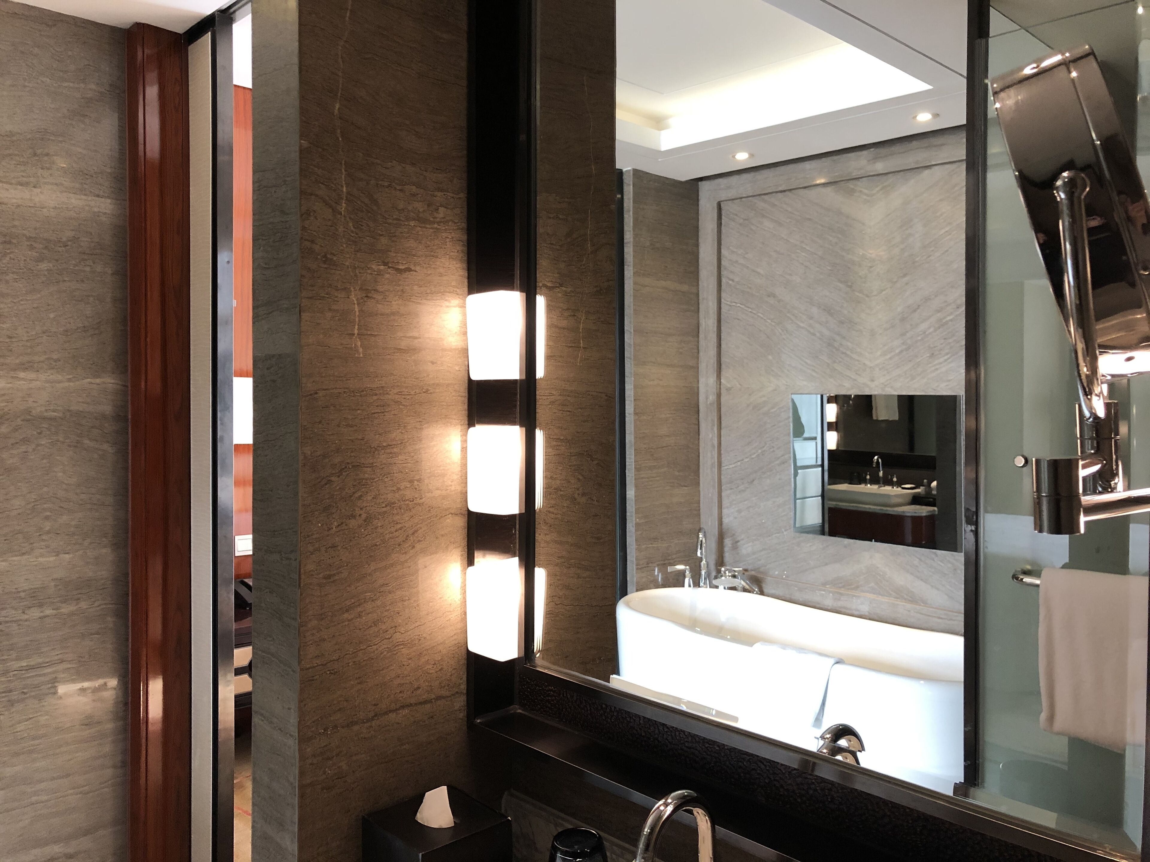 A modern bathroom with a large mirror, a sink, and a towel rack.