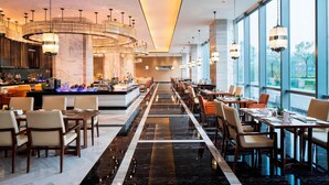Un restaurante moderno con barra central, mesas largas para comer y lámparas colgantes.