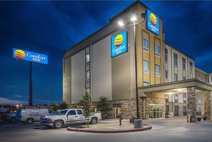 A Comfort Inn hotel with a modern design, featuring a prominent sign, a parking area with a white truck, and a well-lit entrance.