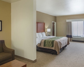 A hotel room with a bed, a chair, a bedside table, a lamp, and a window with curtains.