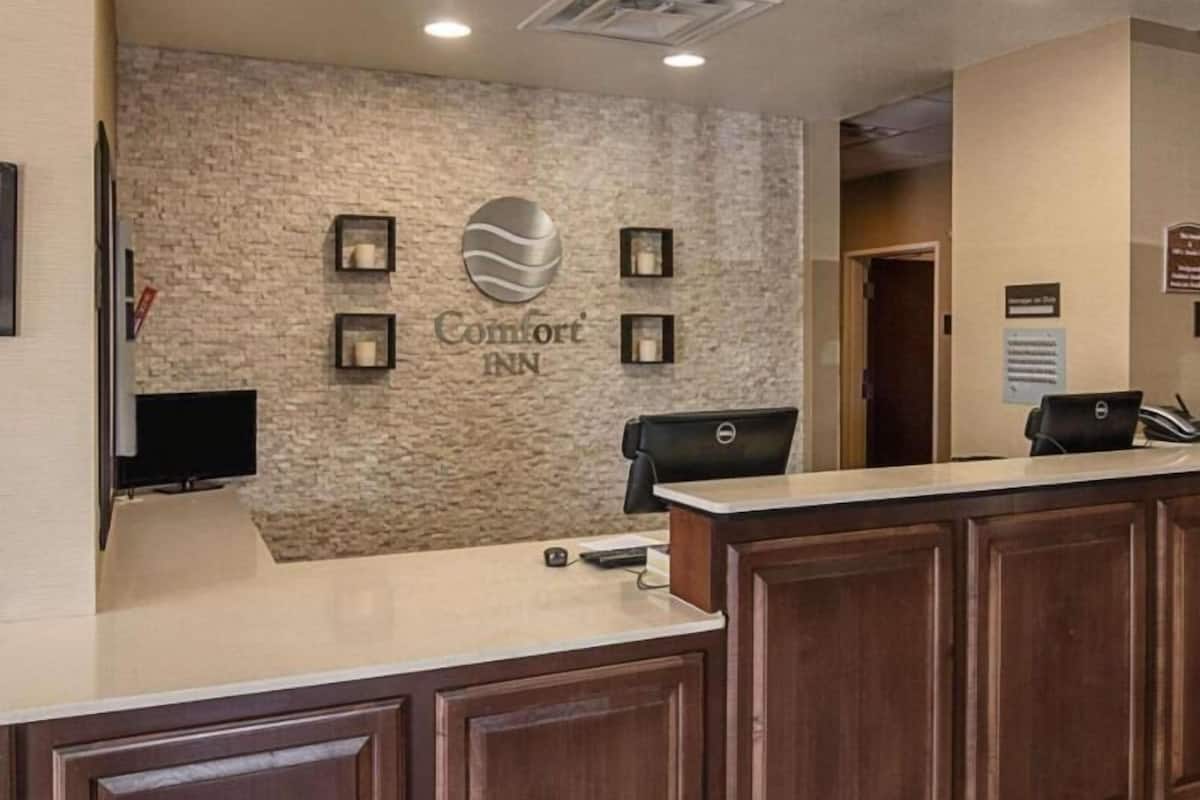 A hotel reception desk with a stone wall, a sign reading 'Comfort Inn,' and a flat-screen TV.