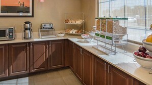 A hotel kitchen with breakfast items, a coffee machine, and a window with a view. - Comfort Inn Midland South I-20 (Midland)