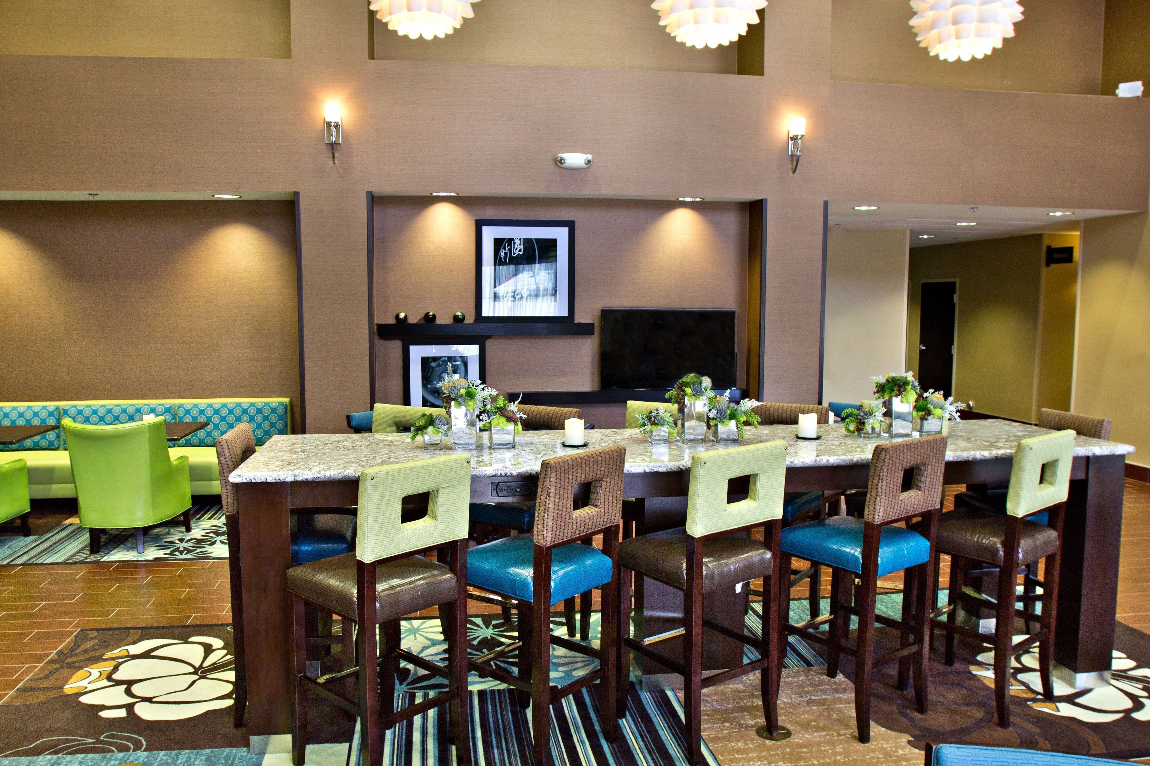 Un comedor de hotel con una mesa larga, varias sillas y un sofá al fondo.