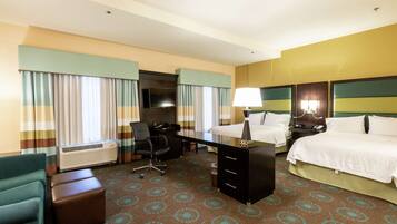 A hotel room with a bed, a desk, a chair, a dresser, and a TV.