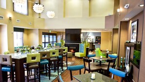 A restaurant with multiple seating areas, including booths and tables, a fireplace, and a television screen. - Hampton Inn & Suites Salt Lake City/Farmington (Farmington)