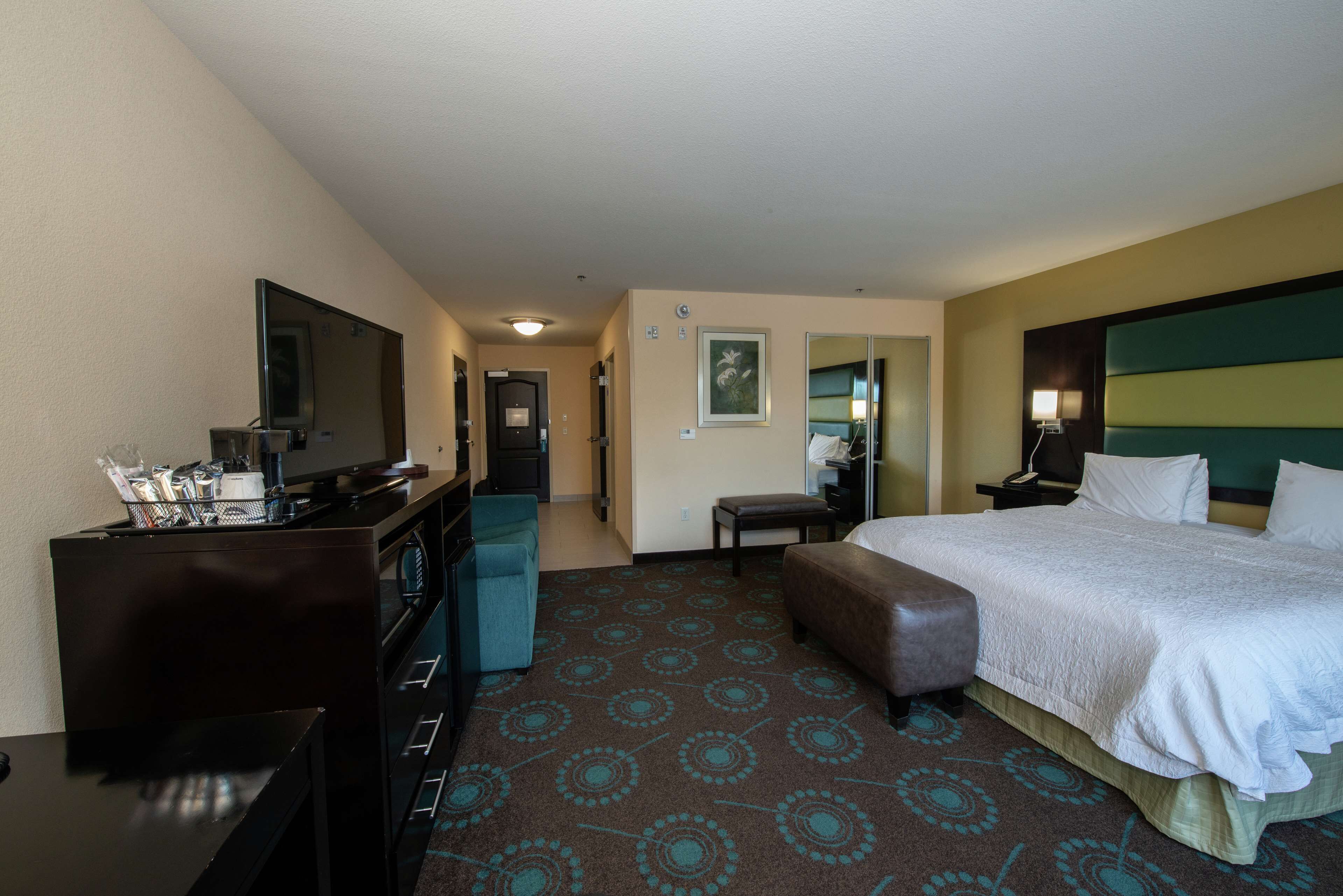 Habitación de hotel con cama, escritorio con silla, televisión, mesita pequeña y sofá.