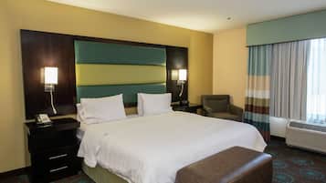 Habitación de hotel con una cama grande, dos mesitas de noche, una silla, un escritorio y una ventana con cortinas.