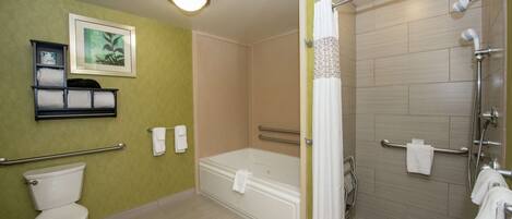 A bathroom with a toilet, a bathtub, a shower with grab bars, and a towel rack.