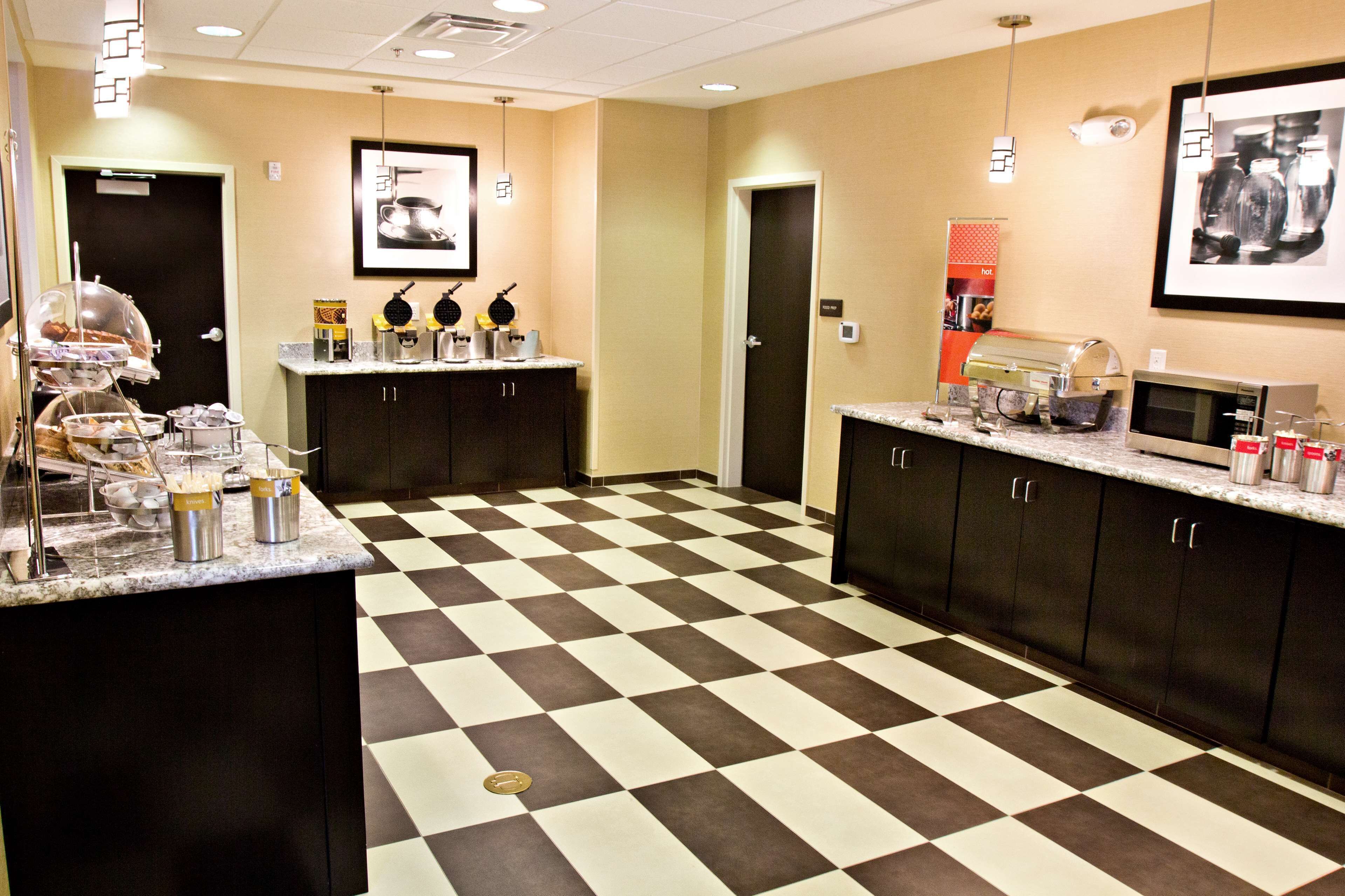 A hotel kitchen with checkered flooring, a coffee station, and a microwave.